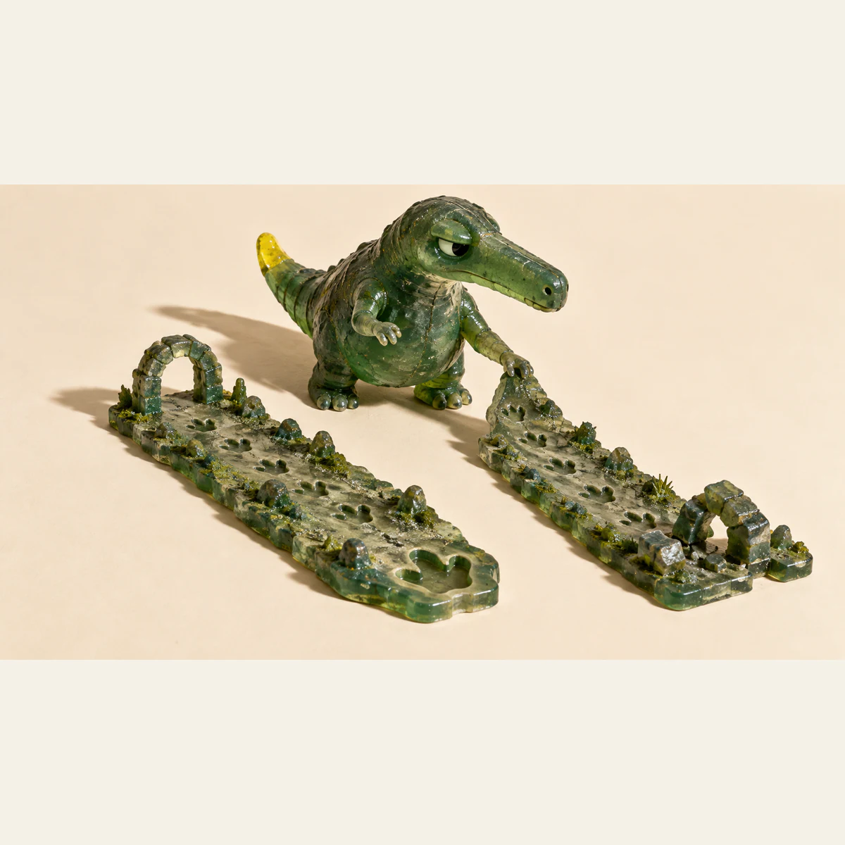 A skeptical green resin dinosaur grips one of two footprint-covered miniature paths. One path has an intact arch, the other a partly collapsed arch, with hard shadows across an ivory background.