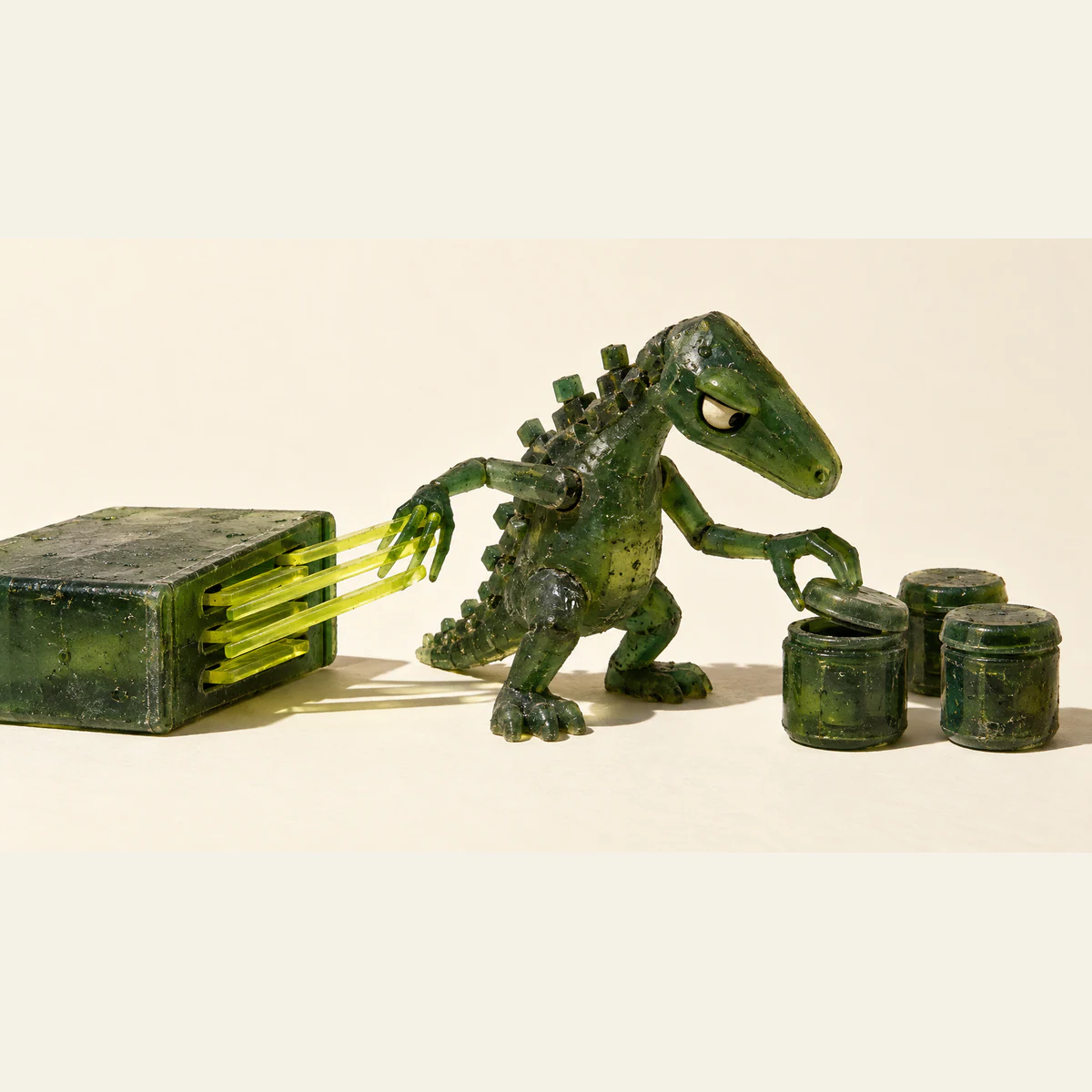 A skeptical green resin dinosaur pulls several yellow strips from a slotted block while lifting one jar lid beside two closed jars, on an ivory background.